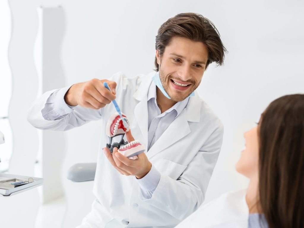 Cheerful-doctor-showing-how-to-brush-teeth-using-jaw-model. Jpg